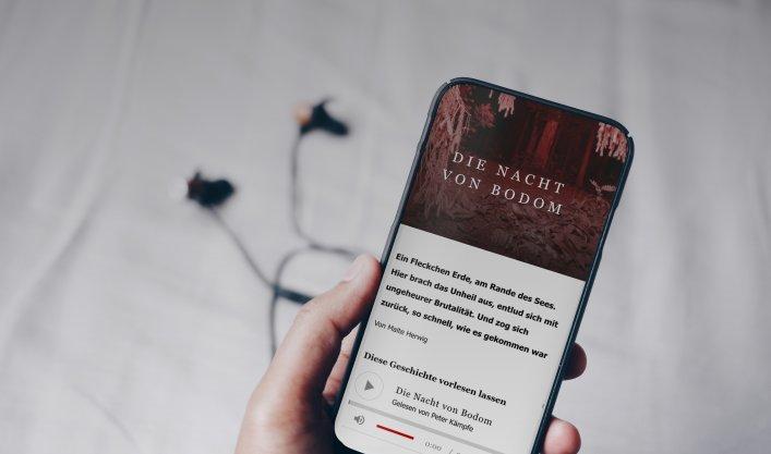 Eine Hand hält ein Smartphone, auf dem ein Artikel inkl. Vorlesefunktion zu sehen ist