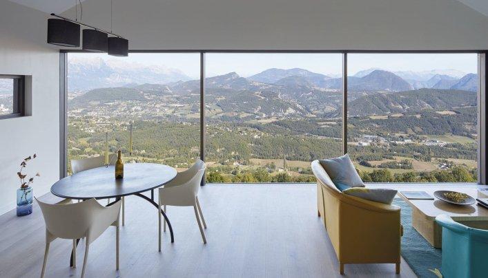 Bild eines Zimmers mit Fensterfront und einer Landschaft im Hintergrund