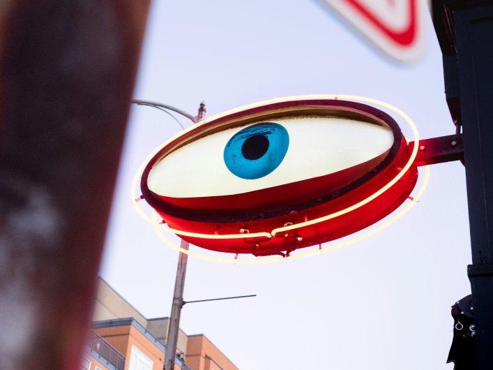 Eingangsschild über Ladentür, das einem Auge ähnelt