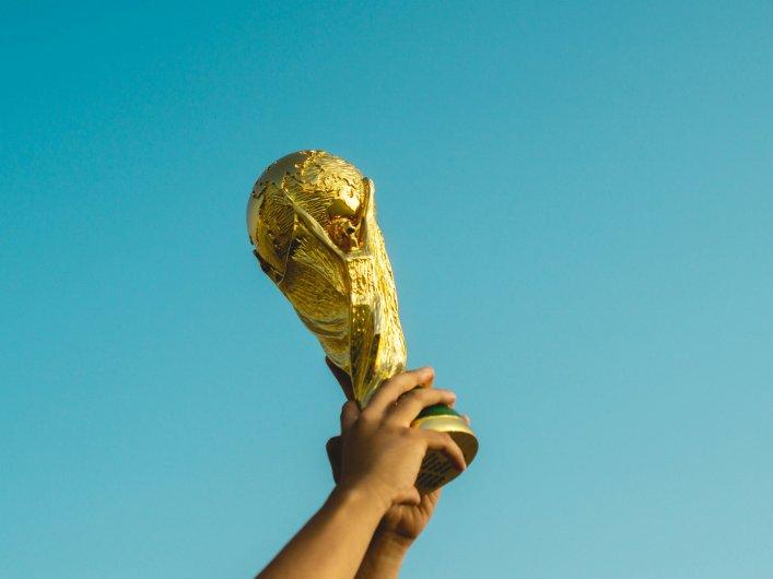 Hand hält einen goldenen Pokal in den Himmel, Symbol für Erfolg und Eigenverantwortung mit einem Open Source CRM.