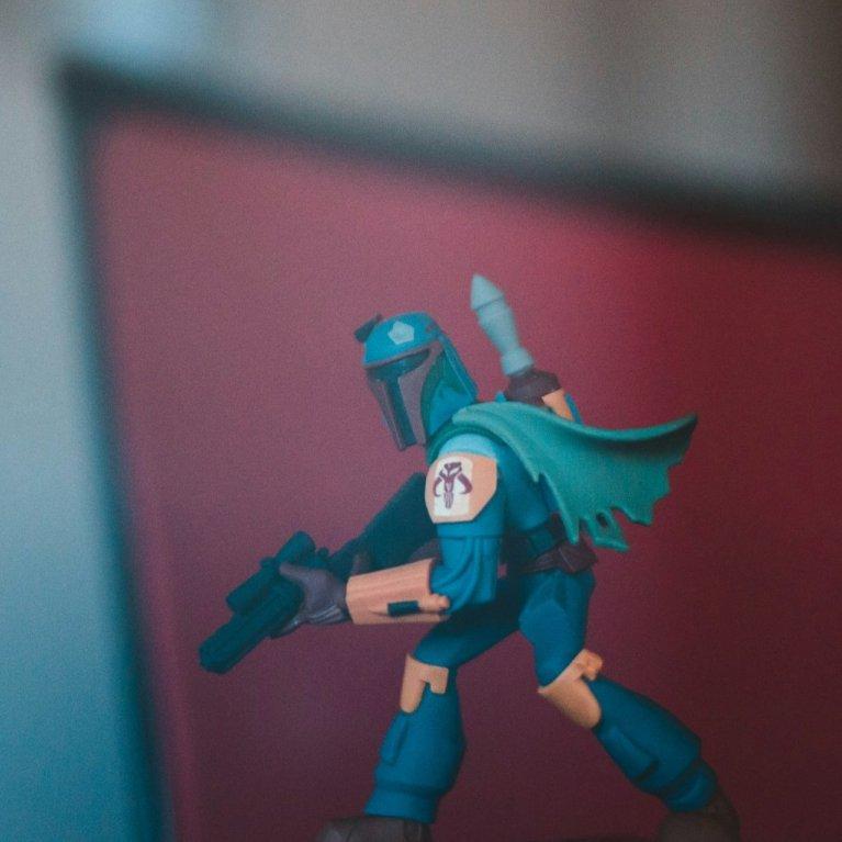 Actionfigur eines mandalorianischen Charakters vor unscharfem roten Hintergrund.