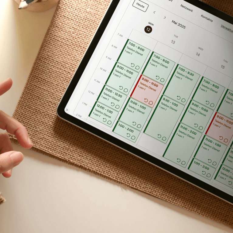 Sicht von oben auf einen Schreibtisch, auf dem die Hände einer person eine Tasse Kaffee halten und dabei mit einem Stift auf einem Tablet arbeiten. 