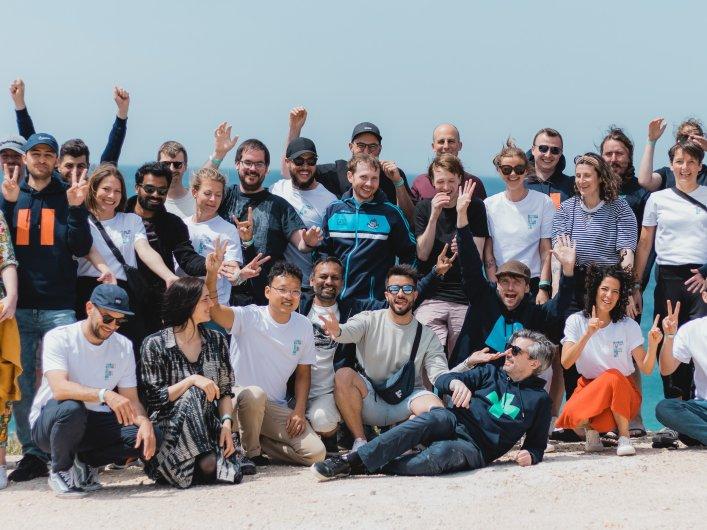 Eine Gruppe von Personen posiert für ein Foto am Strand, repräsentiert das Team von Factorial.